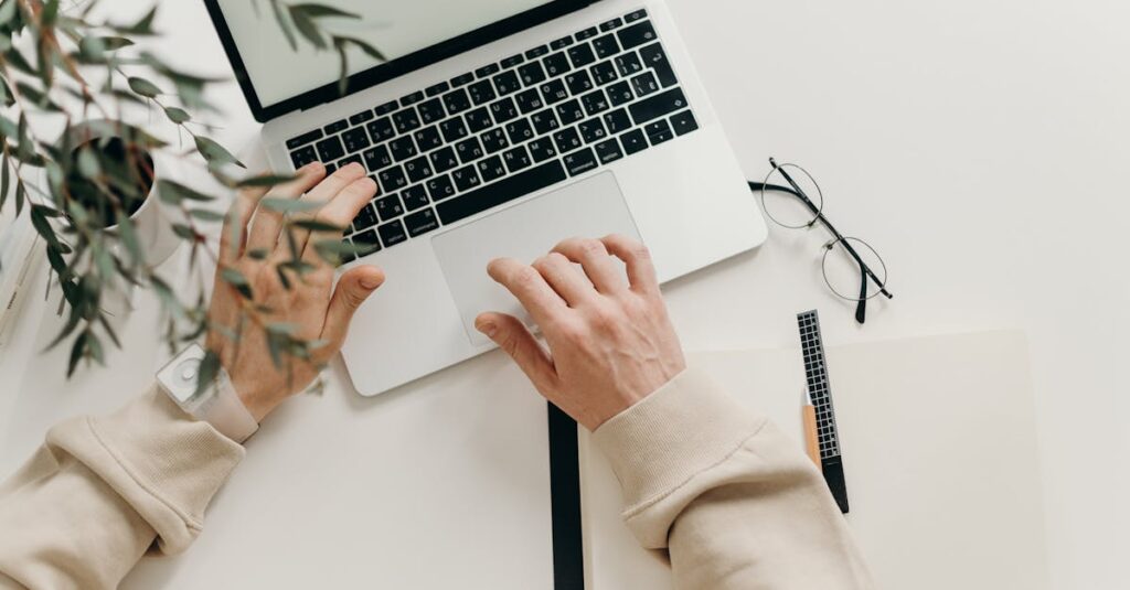 An overhead view of a person working on a laptop in a minimalist home office setting.