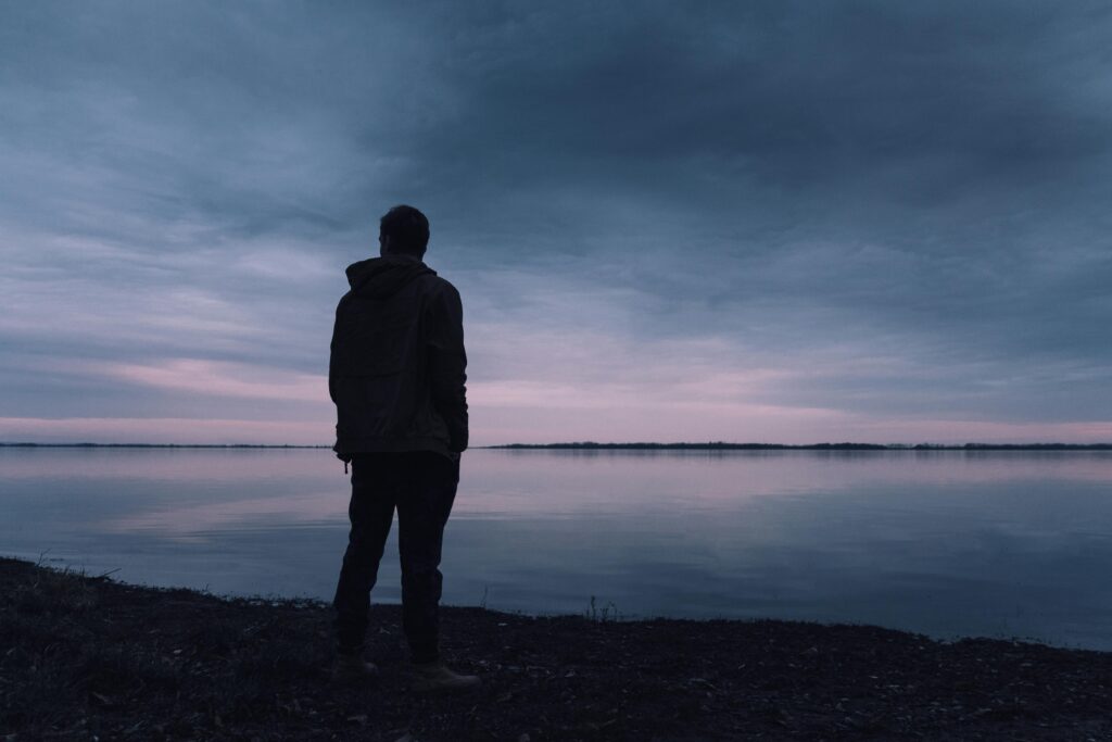 pexels-photo-670720-670720 A solitary silhouette of a man in a jacket gazing at a lake during a peaceful sunset, creating a serene atmosphere.