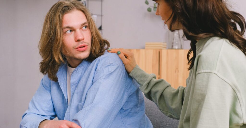 Concentrated woman talking and touching shoulder of pensive male in light room in daytime